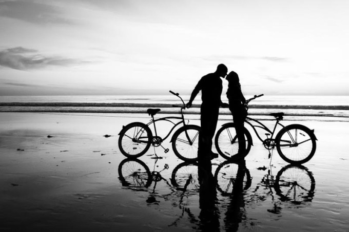 Silhouette picture of a young couple kissing on beach with bicycles