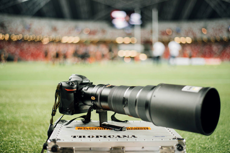 a high end digital camera with long lens for sports photography