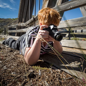 Intermediate photography student laying on the ground to get the shot