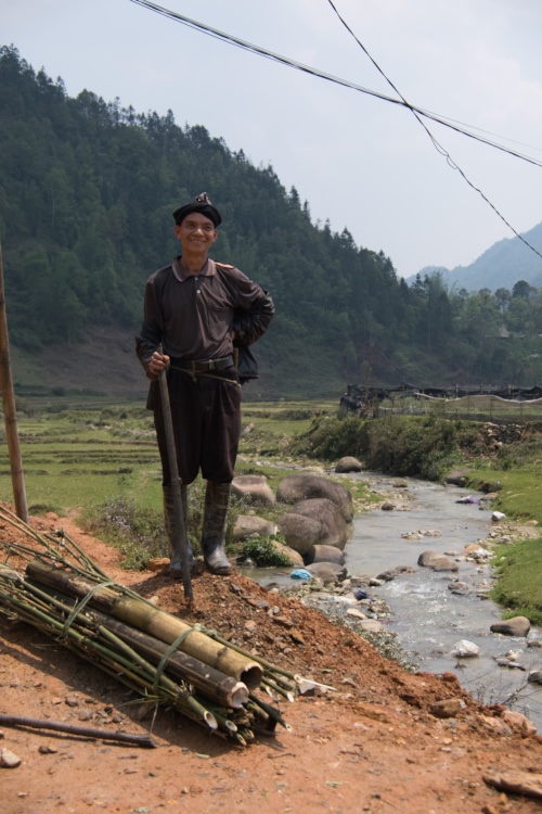 Vietnamese villager standing beside a stream with powerlines overhead