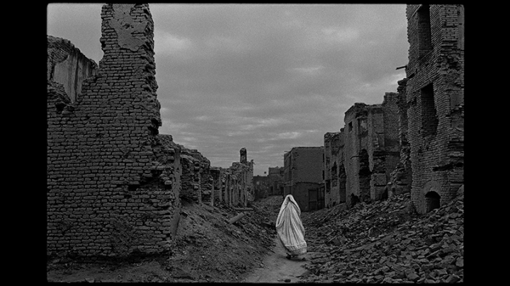 A woman in a burqa walking through a ruined street in Afghanistan, 1996 by James Nachtwey
