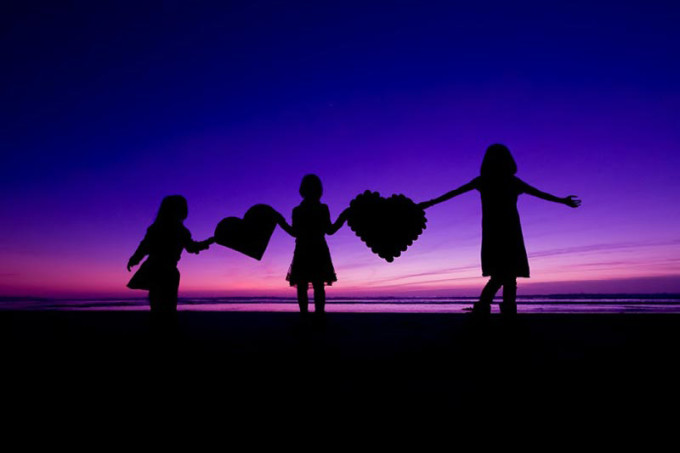 silhouette picture of children on a beach with hearts