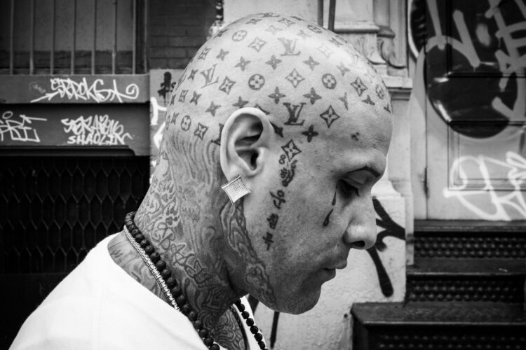 black and white photo of a bald man with his head covered in tatoos