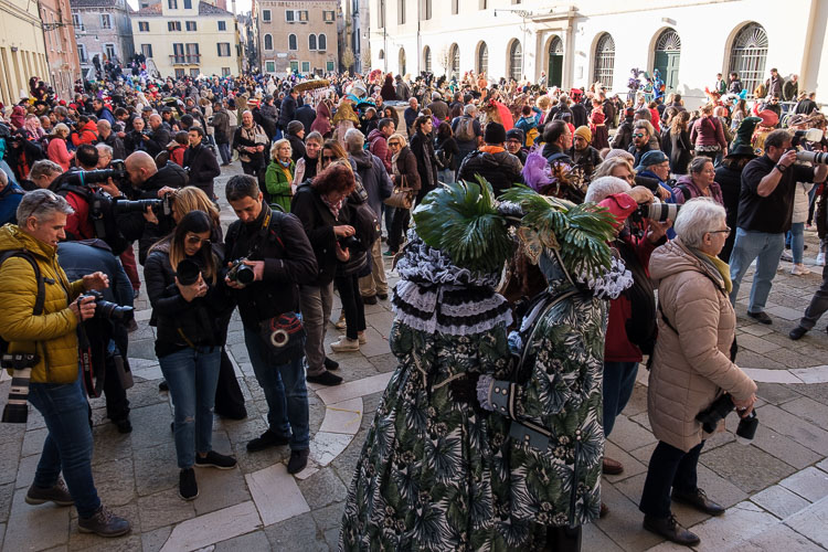 a square in Venice with crowds of photographers and masked costumed characters