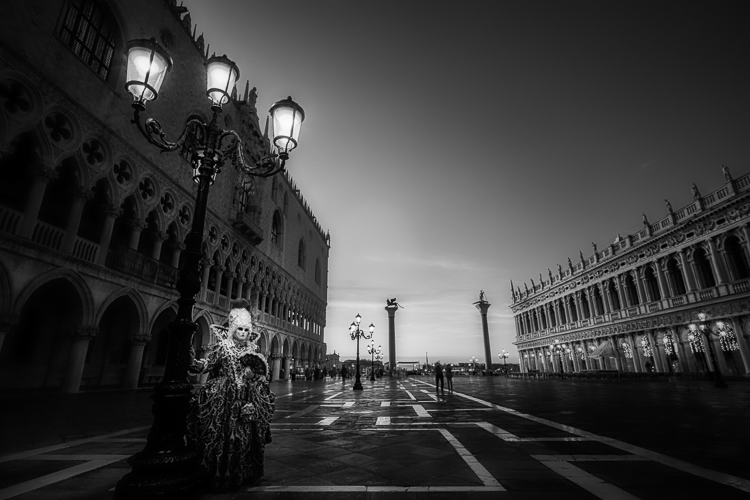 infrared photo of character in costume under old fashioned street lamp in St Marks square, Venice Italy