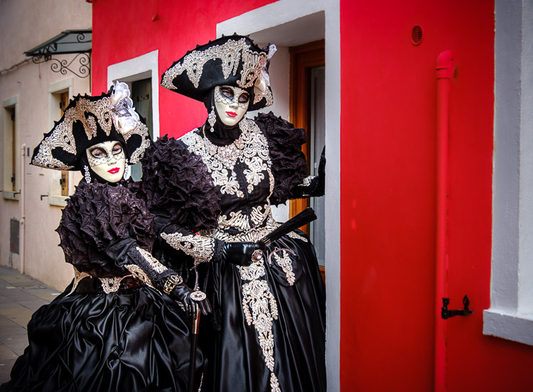 husband and wife dressed as females in costumes and masks at venice carnival