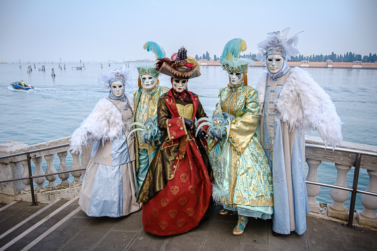 Several costumed and masked characters pose on a bridge at the grand canal