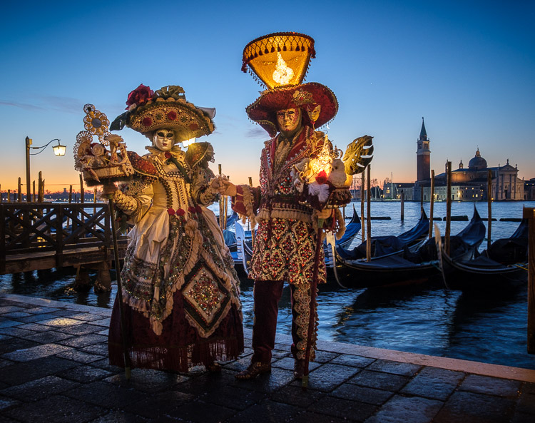 Characters in costumes and masks at sunrise in Venice during Carnival