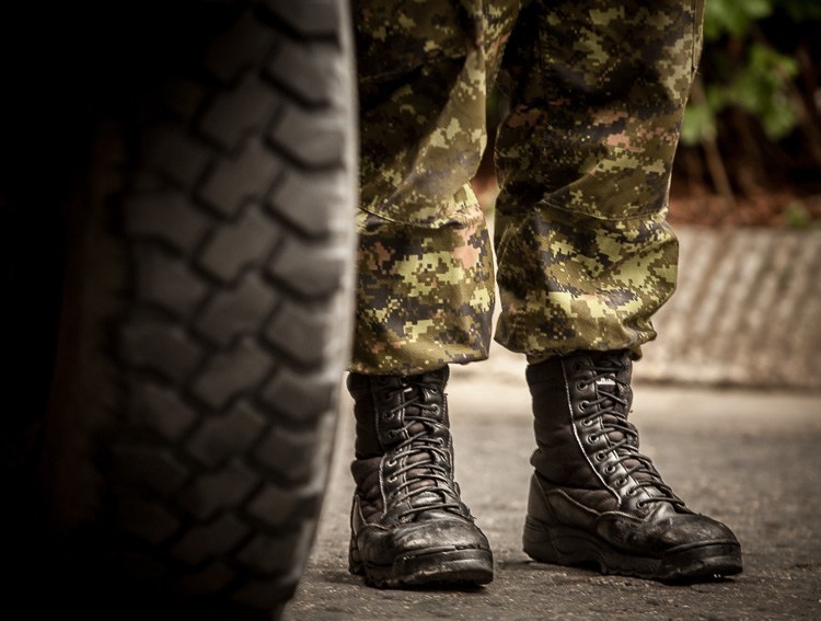A military man in fatigues shows of his boots