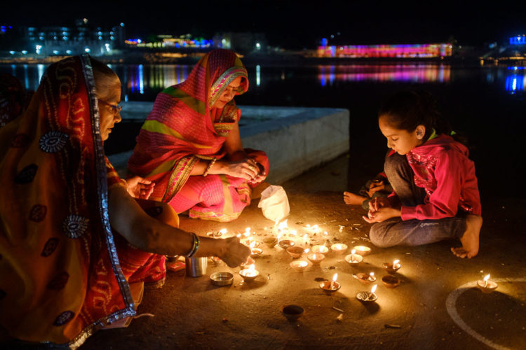 Indian women lighting candles on the edge of a river at night
